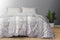 A king size bed sheet set with pillow covers featuring a floral pattern, displayed on a bed with a gray wall in the background and a potted plant beside it.